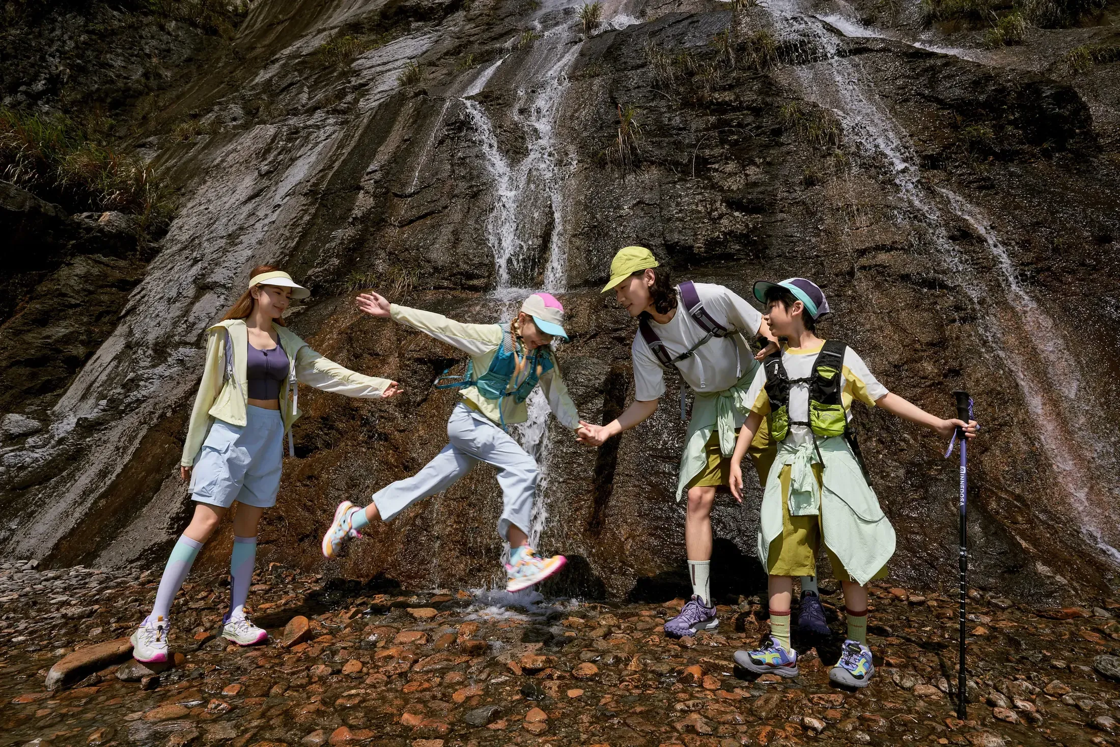 A family helping each other beside a mountain waterfall