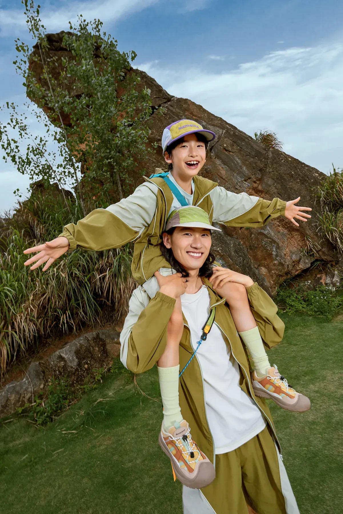 A child riding on an adult's shoulders during a day outside