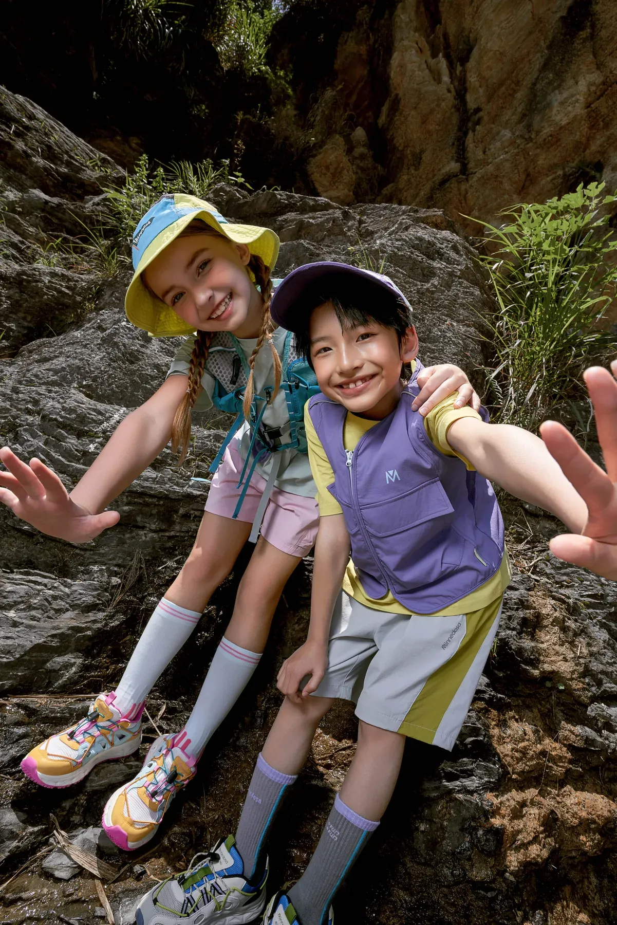 Two young explorers smiling together on a rocky trail
